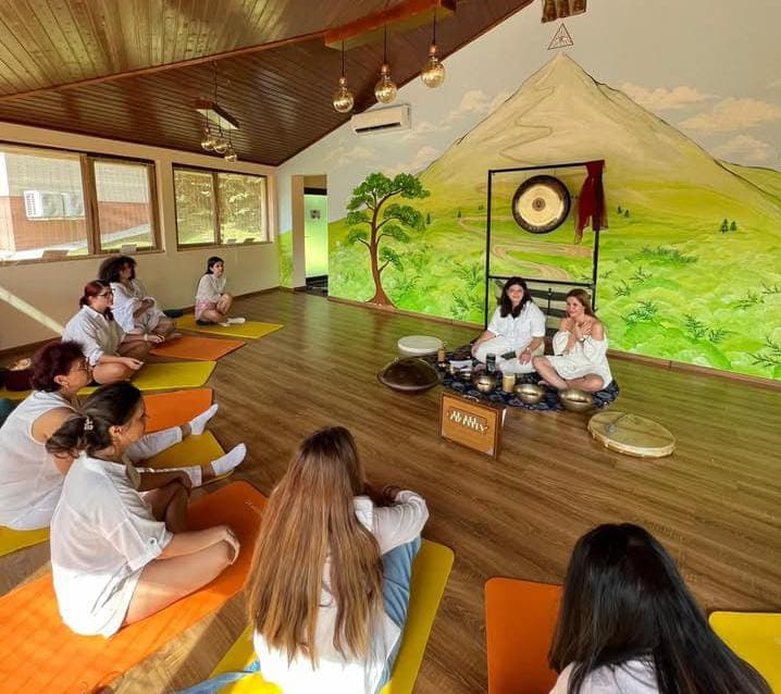Sesiune de sound healing de grup într-o sală cu munte pictat și gong